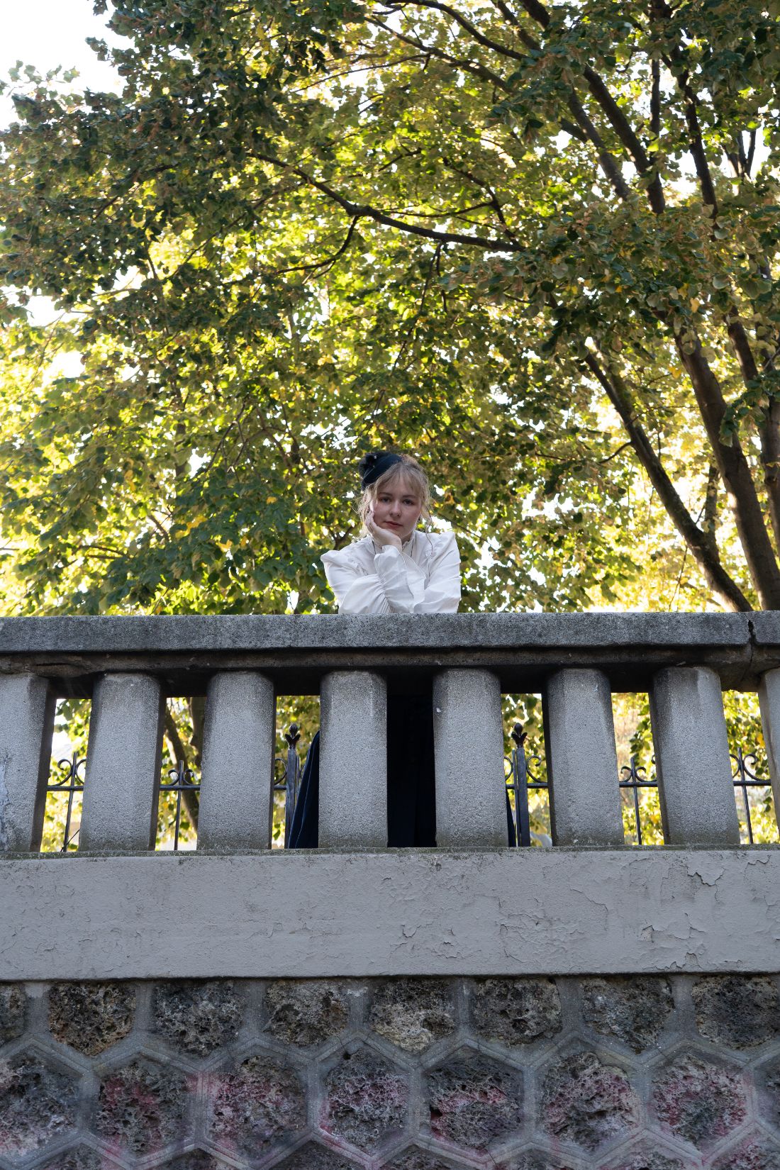 Leaning on a stone balustrade under the trees
